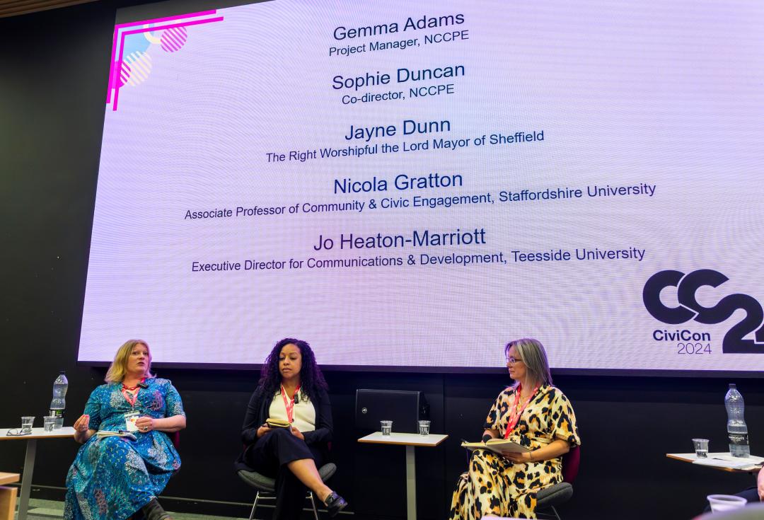 The 5 panel members sitting on chairs on stage for the opening plenary of CiviCon 2024