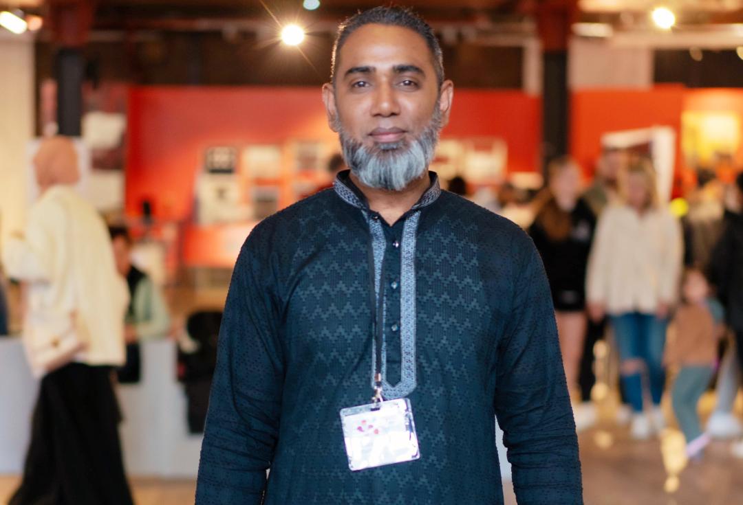 A man standing in a large room, looking directly at the camera