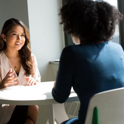 two women talking to each other across a table