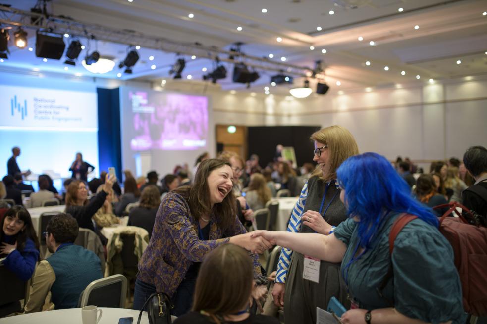 3 people meeting and smiling around a table at Engage conference 