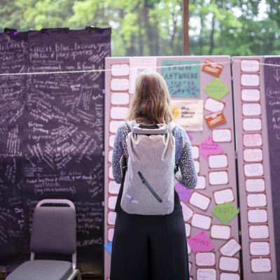 A woman stands in front of a board covered in post-it notes