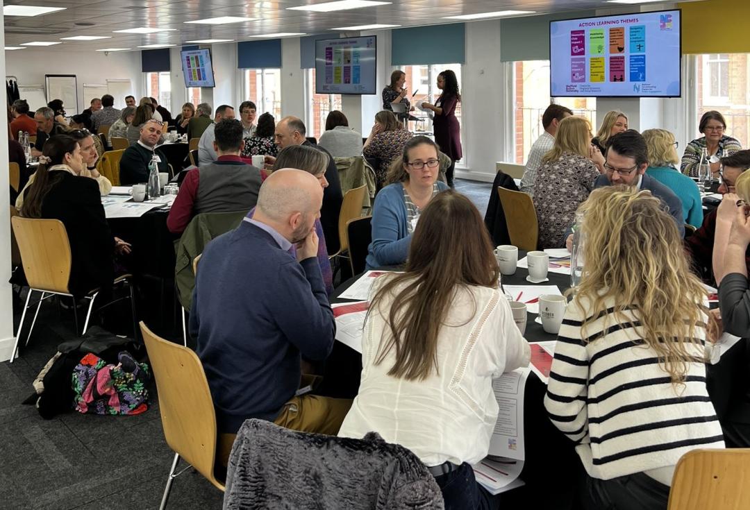 Members of the NCIA action learning groups discussing topics around tables.