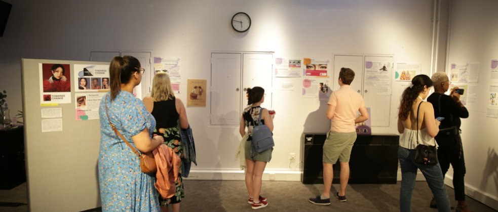 A group of people looking at display boards and posters on a wall